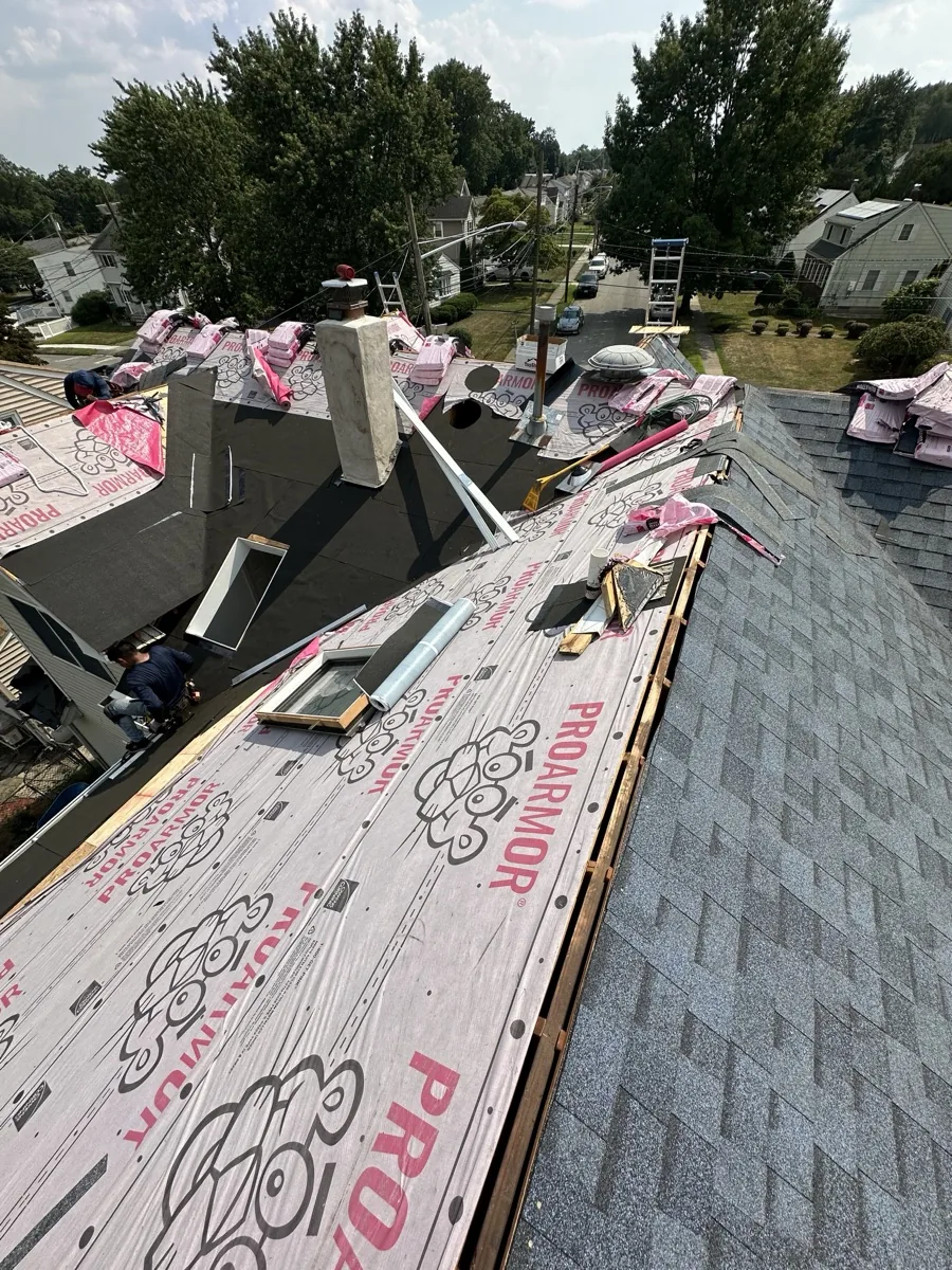 Tear-off in progress with the roof deck exposed and new underlayment going down on a North Jersey home