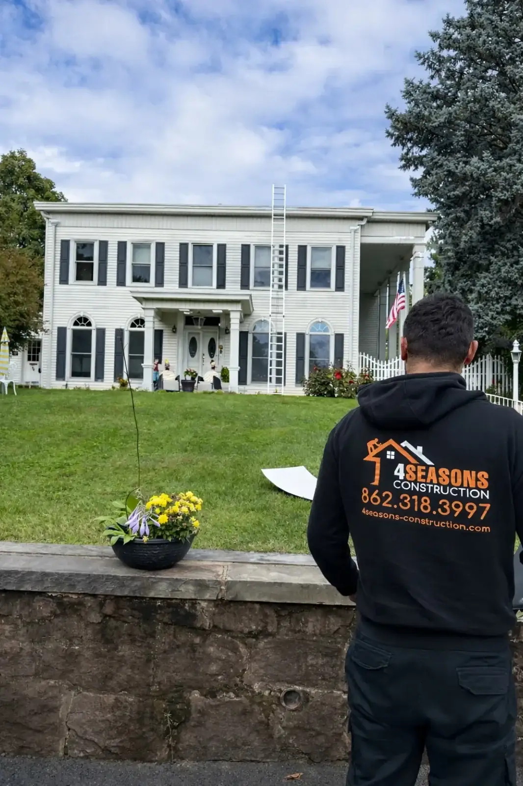 Four Seasons crew member facing a white house with a columned entrance